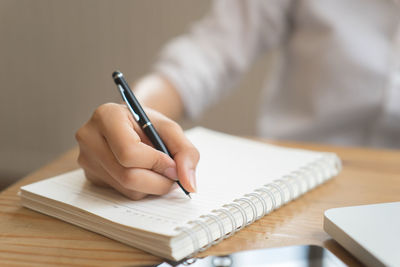 Midsection of woman reading book on table