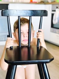 Shirtless boy behind chair at home