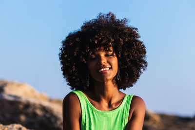 Portrait of smiling woman standing against clear blue sky