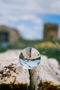 Close-up of crystal ball on rock against sky