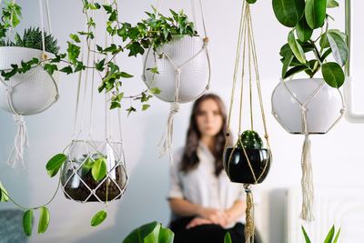 Portrait of beautiful young woman against potted plants at home