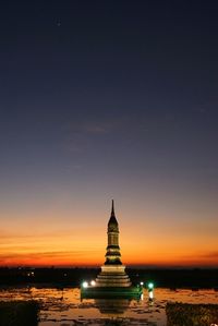 Illuminated column at old ruins against sky at dusk