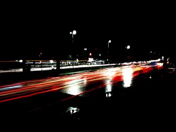 Light trails on street against sky at night