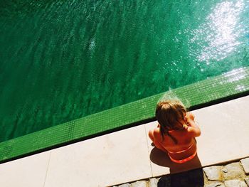 Rear view of girl sitting poolside