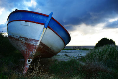 Abandoned boat moored on beach against sky