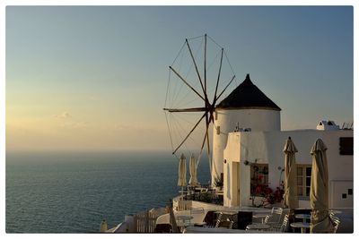 Windmill by sea against sky