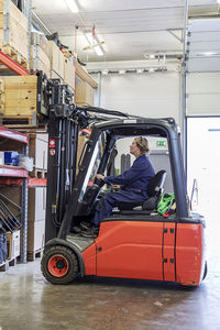 Woman driving forklift truck in warehouse