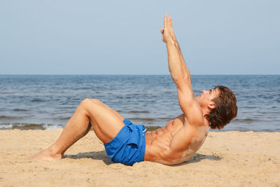 Man doing crunches on sand at beach