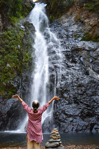 Rear view of woman in waterfall