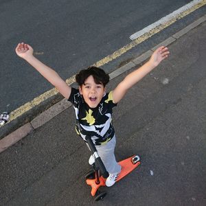 Portrait of boy with push scooter on road