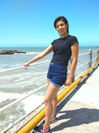 Young woman standing at beach against sky