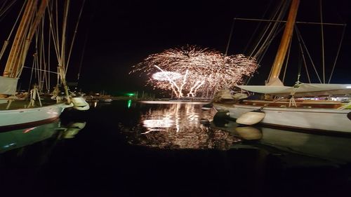 Illuminated boats moored in lake against sky at night