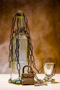 Close-up of glass bottle with chain on table