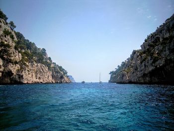 Scenic view of sea and rock formations against clear blue sky