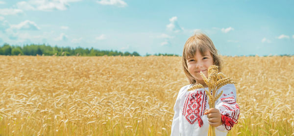 Portrait of smiling young woman standing on field against sky