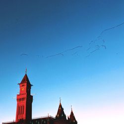 Low angle view of birds flying against blue sky