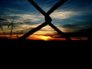 Silhouette of metal fence against dramatic sky