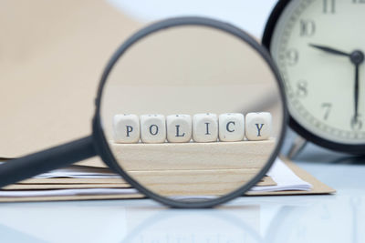 Policy text made of toy blocks with files and magnifying glass on white background