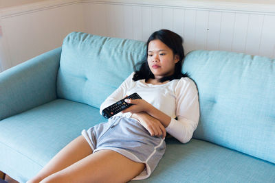 Asian teenage girl sitting boring watch television
