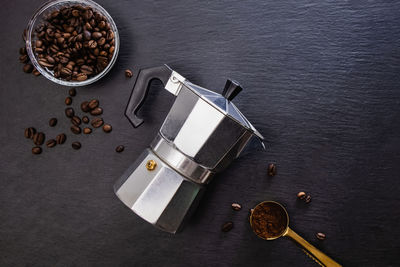 Still life with moka pot and coffee beans on black stone background. ingredients for brewing coffee