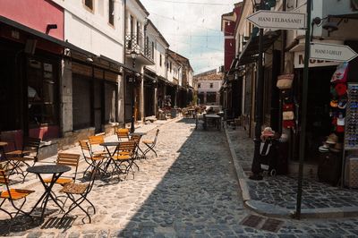 Empty sidewalk cafe amidst buildings in city