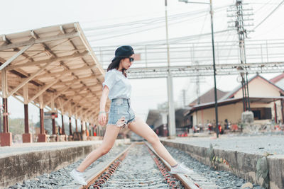 Full length of young woman crossing railroad track