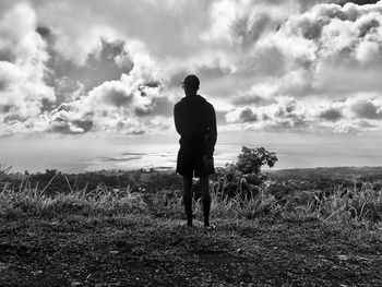 Rear view of man standing on field against sky