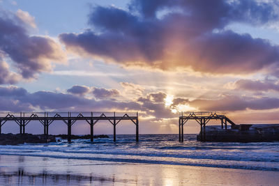 Bridge on the beach at sunset. cloudy sky with copy space.