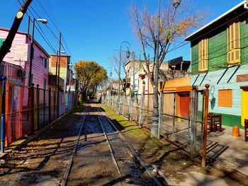 Railroad track amidst bare trees and houses against sky
