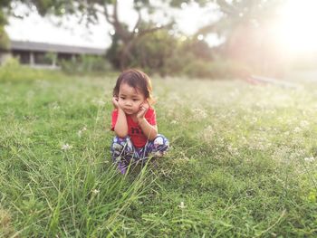 Baby girl crouching on grassy field