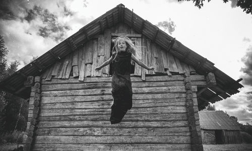 Low angle view of girl jumping against house