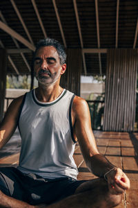 Mature man with eyes closed practicing meditation at wellness resort