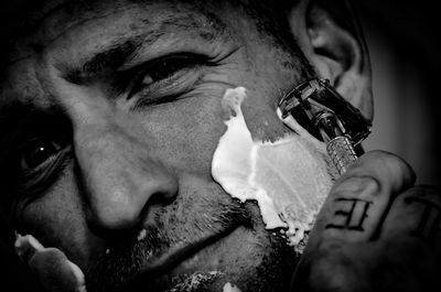 Portrait of man shaving with razor