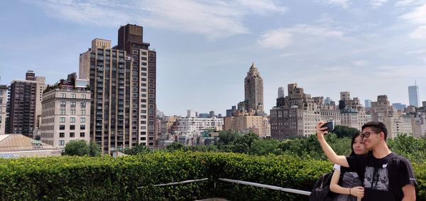 Full length of man photographing in city against sky