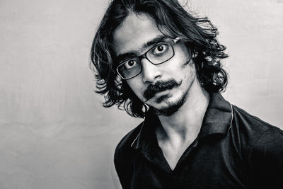 Portrait of young man wearing eyeglasses against white background