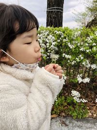 Close-up of cute girl with flower petals on plant