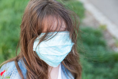 Little blonde girl in a medical mask and in a denim jacket on the street