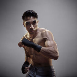 Kickboxer practicing against gray background