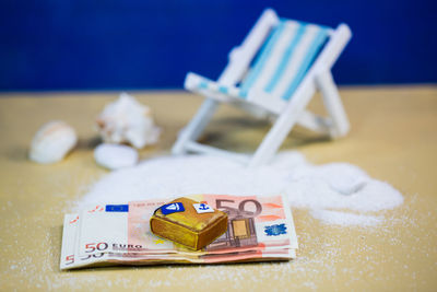 Close-up of paper currency with deck chair on table