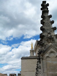 Low angle view of statue of building against cloudy sky