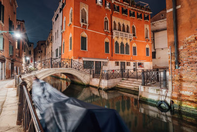 Arch bridge over canal amidst buildings in city