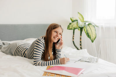 Portrait of young woman using mobile phone while sitting on table at home