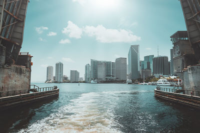 Modern buildings by sea against sky in city