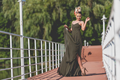 Portrait of woman standing against railing