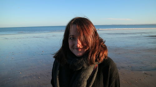 Portrait of beautiful woman at beach against sky