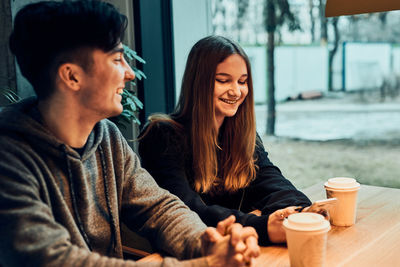 Friends having a chat, talking together, drinking coffee, sitting in a cafe