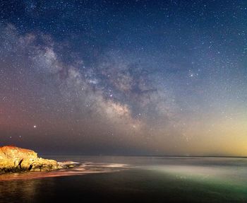 The milkyway shining in the night sky above the maine coastline.