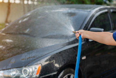 The man use pressor spray water car wash at home in a holiday.