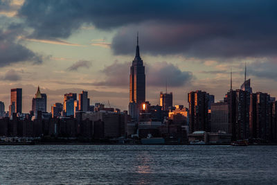 Empire state building and east river against sky during sunset in city