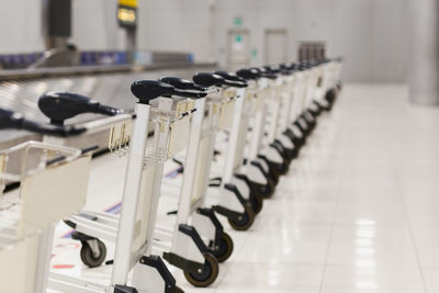 Empty airport luggage carts parking behind warning line in baggage claim area in terminal.